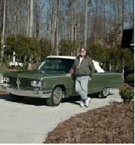 A man standing next to an old green car.